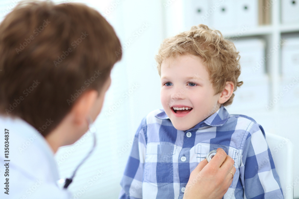 Young male doctor auscultating a little boy by stethoscope. Health care, insurance and help concept. Young male doctor auscultating a little boy by stethoscope. Health care, insurance and help concept.