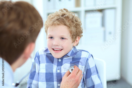 Doctor examining a school boy chest by stethoscope at hospital office.