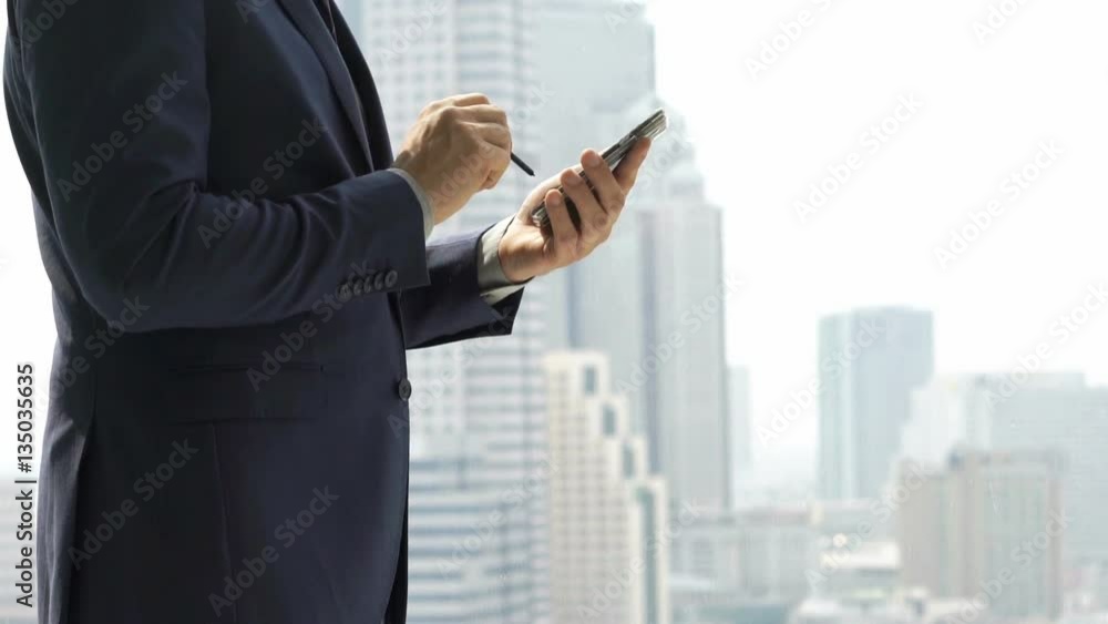 Businessman texting on smartphone with stylus pen standing by window in office
Businessman texting on smartphone with stylus pen standing by window in office