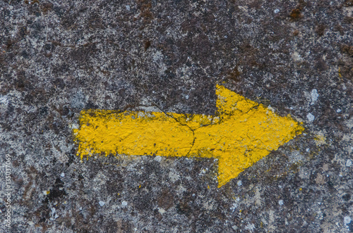 Yellow arrow painted in a wall directional sign in camino de san