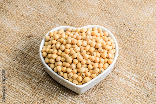 soybeans in heart ceramic bowl on sackcloth background..