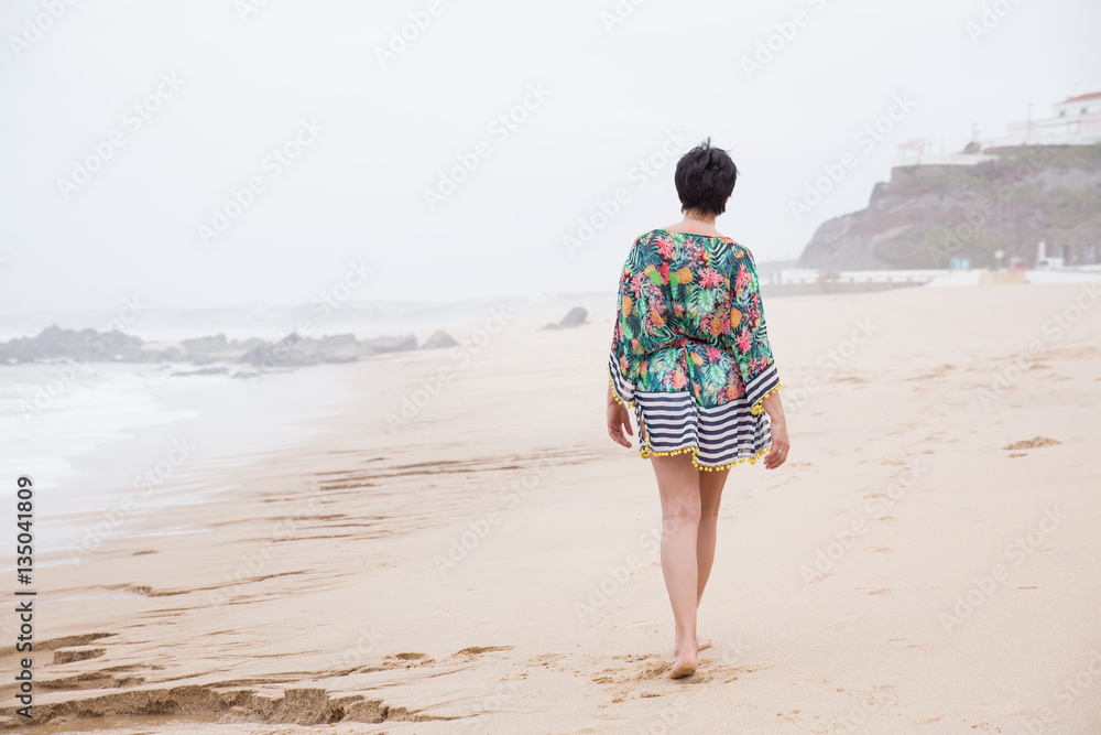 Happy healthy mature woman walking, Enjoying freedom on the Ocean Beach. Travel Vacation. Wellness and Happiness Lifestyle Concept Happy healthy mature woman walking, Enjoying freedom on the Ocean Beach. Travel Vacation. Wellness and Happiness Lifestyle Concept