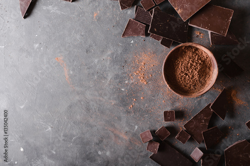 Chocolate  chunks and cocoa powder. Chocolate bar pieces.  A large bar of chocolate on gray abstract background. Background with chocolate. Slices of chocolate, Sweet food photo concept. Copyspace