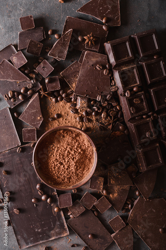 Chocolate chunks and cocoa powder. Coffee beans Chocolate bar pieces. Large bar of chocolate on gray abstract background. Background with chocolate. Slices of chocolate. Sweet food photo concept.