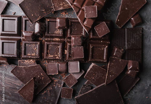 Chocolate chunks. Chocolate bar pieces.  A large bar of chocolate on gray abstract background. Chocolate candies. Background with chocolate. Slices of chocolate. Sweet food photo concept. Copyspace