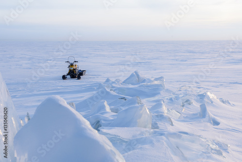 Snowmobile standing on the frozen lake, pieces of ice and frost.