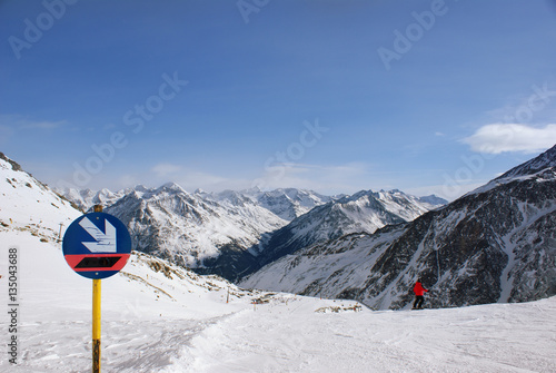 Sign descent on the slopes in the Alpine mountains, the person is going to go down skiing, many mountain peaks ahead