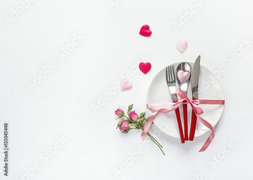 Romantic festive table setting with cutlery, roses and hearts on