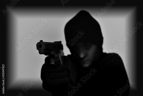 Fototapeta Female robber with black tights over her head holding a gun and aiming