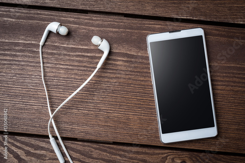 Smart phone and earphones on wooden table