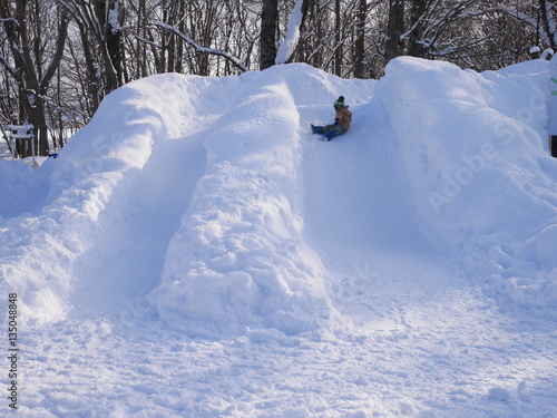 A boy playing on a snow mountain with sliding chutes