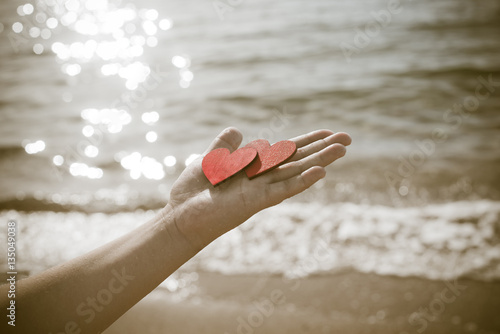 two red hearts on the palm of the girl on sea wave background 