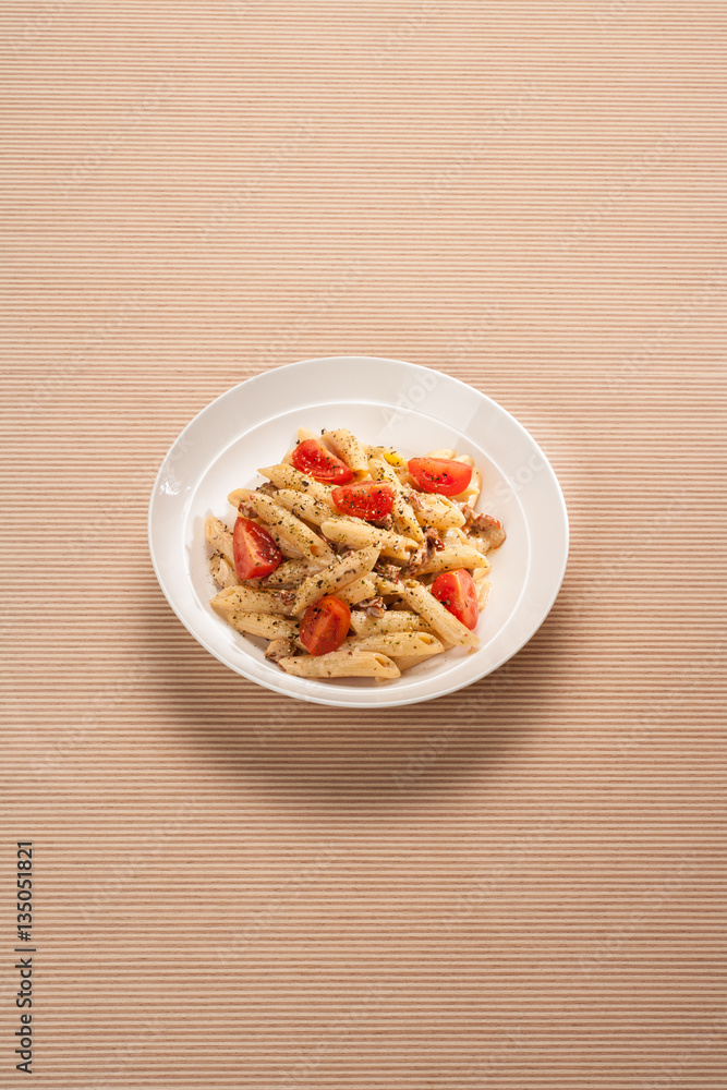 Cheese and mushroom pasta with tomatoes. On striped wooden background. Cheese and mushroom pasta with tomatoes. On striped wooden background.