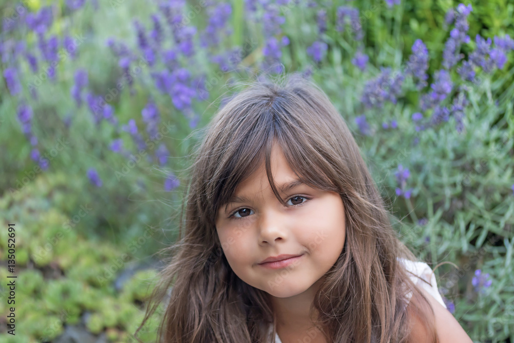 High angle view of cool brunette little girl with violet lavender flower in the background. High angle view of cool brunette little girl with violet lavender flower in the background.