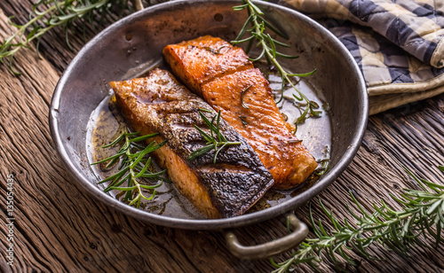 Salmon fillets. Grilled salmon, sesame seeds herb decorationon on vintage pan or black slate board. fish roasted on an old wooden table.Studio shot. photo