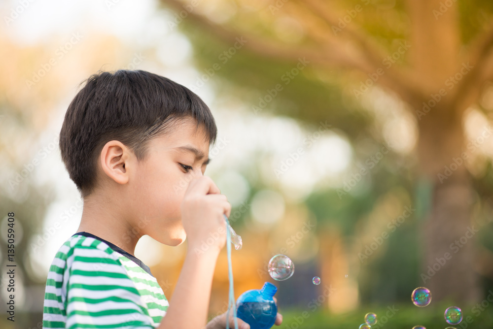 Little boy blowing bubbles soap in the park Little boy blowing bubbles soap in the park