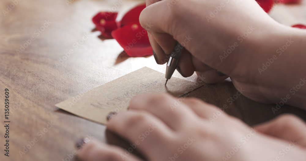Obraz premium girl writes mothers day on a paper card on old wood background, 4k photo