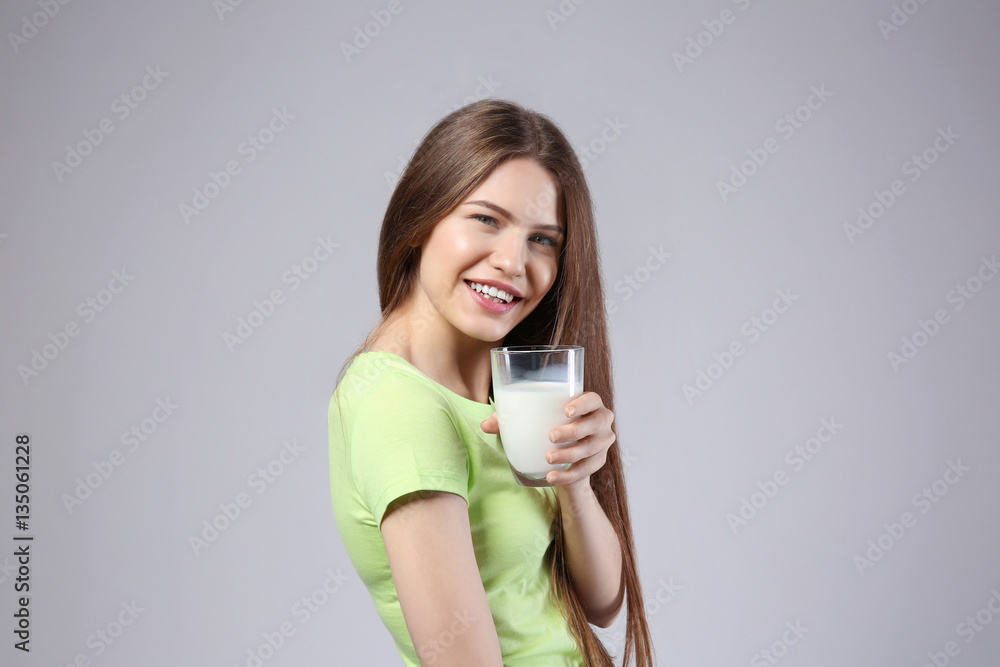 Beautiful young woman with glass of milk on grey background Beautiful young woman with glass of milk on grey background