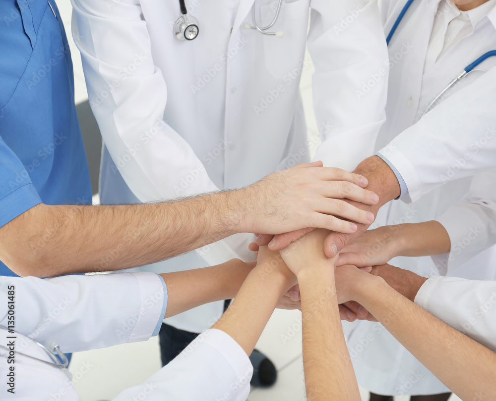 Team of doctors putting hands together, closeup Team of doctors putting hands together, closeup