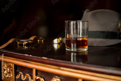 Glass of whiskey and men's watches on the wooden retro table
