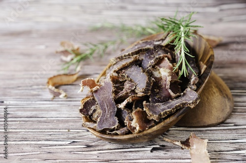 jerked meat, cow, deer, wild beast or biltong in wooden bowls on a rustic table photo
