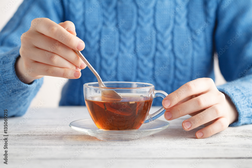 Young woman hold glass cup oа tea on table