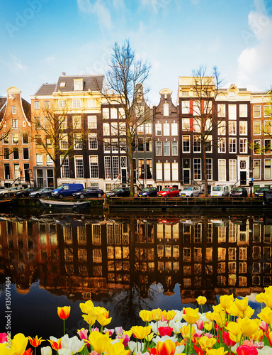 Photography Facades of dutch houses over canal with mirror reflections and tulip flowers, Am