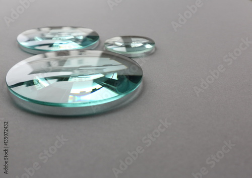 Optical glass lenses on grey background with reflections