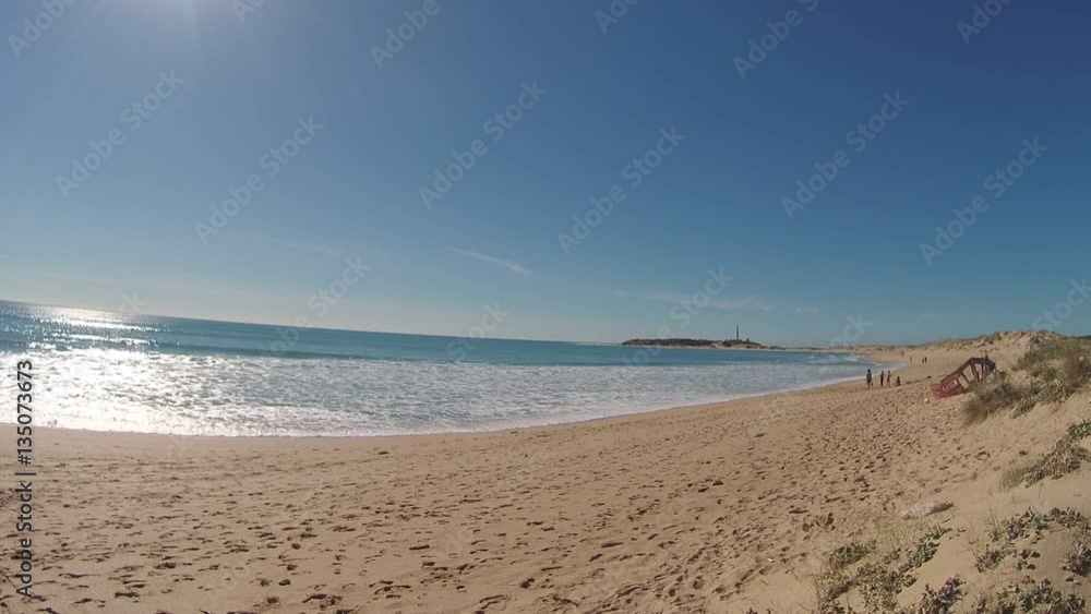 Unrecognizable people on the beach, with the Trafalgar lighthouse in the background, on the coast of Cadiz, Spain Unrecognizable people on the beach, with the Trafalgar lighthouse in the background, on the coast of Cadiz, Spain
