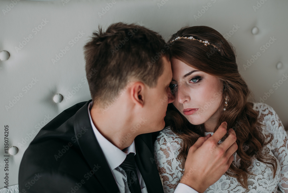 cute wedding couple in the interior of a classic white studio decorated. hey kiss and hug each other, holding hands looking at each other cute wedding couple in the interior of a classic white studio decorated. hey kiss and hug each other, holding hands looking at each other