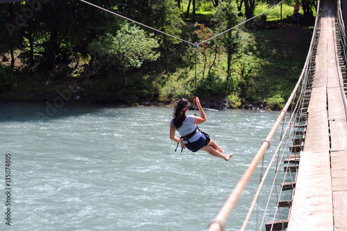 Canvas Print woman crossing a river with tyrolean traverse