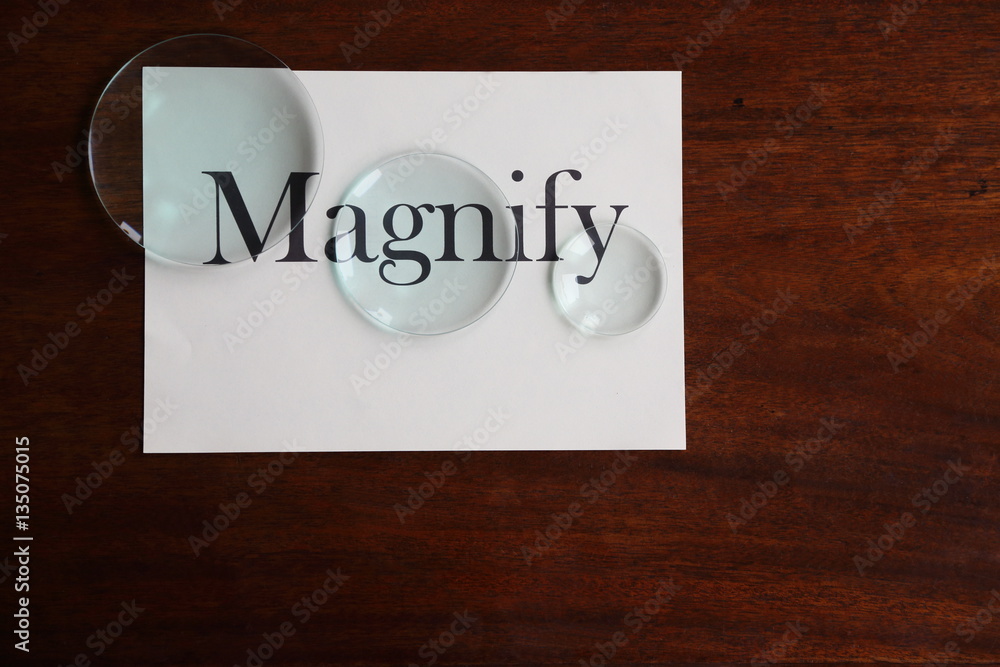 Magnify broad text on white sheet with glass lenses on antique desk Magnify broad text on white sheet with glass lenses on antique desk
