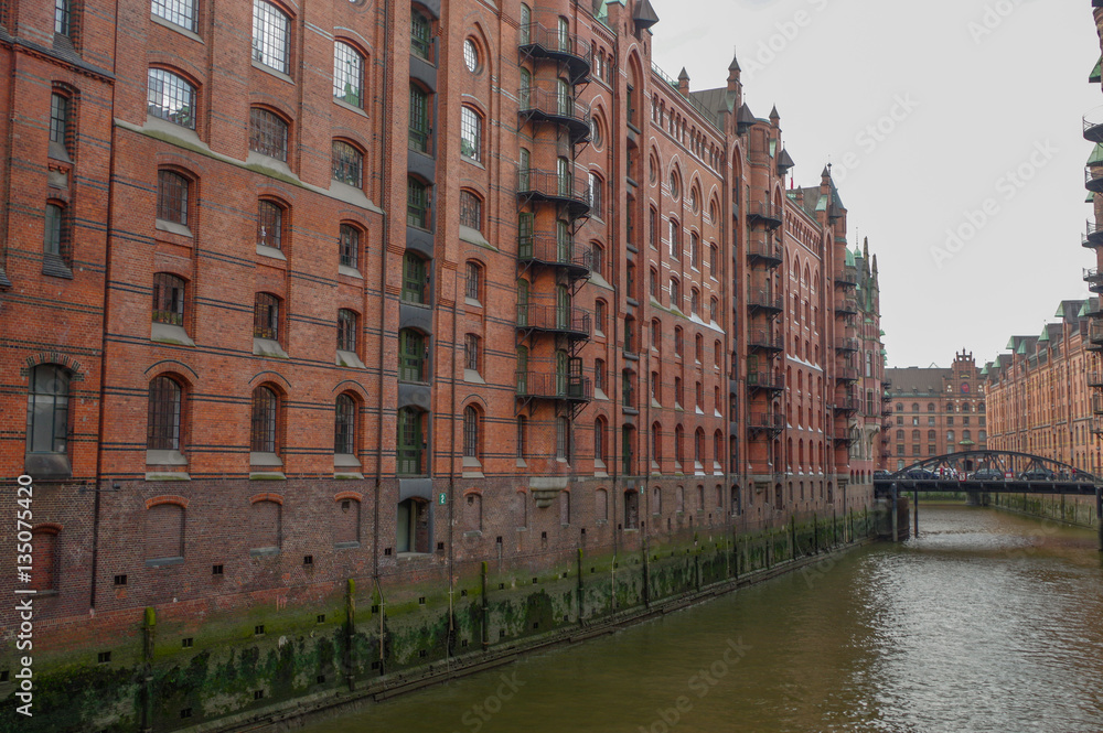 HAMBURG, GERMANY - JULY 18, 2015: the canal of Historic Speicherstadt houses and bridges at evening with amaising skyview over warehouses, famous place Elbe river.