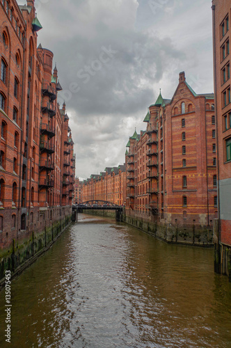 HAMBURG, GERMANY - JULY 18, 2015: the canal of Historic Speicherstadt houses and bridges at evening with amaising skyview over warehouses, famous place Elbe river. © evolutionnow