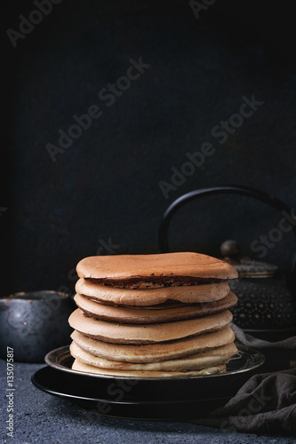 Wallpaper Mural Stack of homemade american ombre chocolate pancakes served on black plate with jug of cream and teapot over black stone texture background. Torontodigital.ca