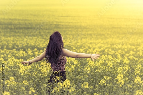 Beautiful lovely free woman in sunny summer nature from behind. Attractive happy young girl enjoying the warm summer sun and her health in a wide green and yellow meadow. Part of series © azur13