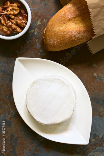 Camembert Käse mit Baguette und Walnuss an der Seite, fotografiert mit natürlichem Licht