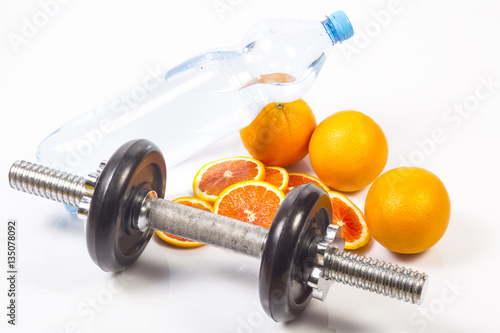 Concept of healthy active lifestyle. red oranges and slices. Bottle with pure drinking water. Fitness dumbbell. White background.