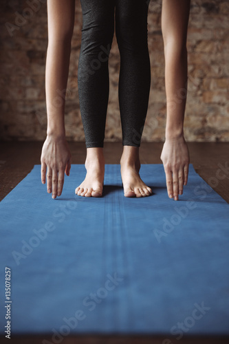Fitness woman standing barefoot and stretching on mat