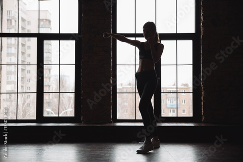 Silhouette of woman athlete standing and doing shadow boxing exercises