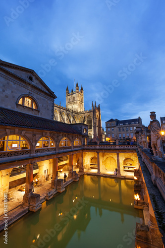 The Roman Baths and Bath Abbey at night in Bath, England, UK.