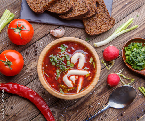 Beet soup in wooden plate with vegetables photo