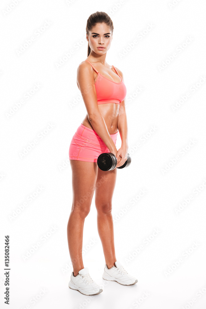 Full length portrait of a young sportswoman holding heavy dumbbell Full length portrait of a young sportswoman holding heavy dumbbell