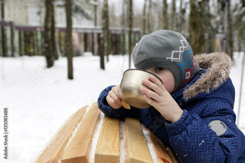 Kid drinking tea in winter