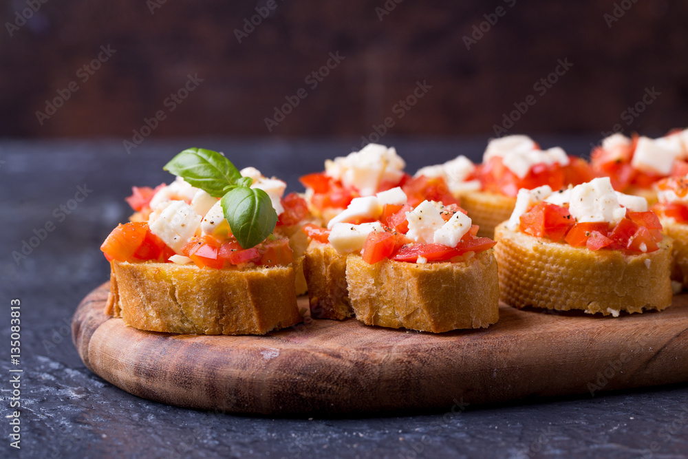 Bruschetta small sandwiches antipasto set with tomato, mozzarella, garlic and basil on black background Bruschetta small sandwiches antipasto set with tomato, mozzarella, garlic and basil on black background
