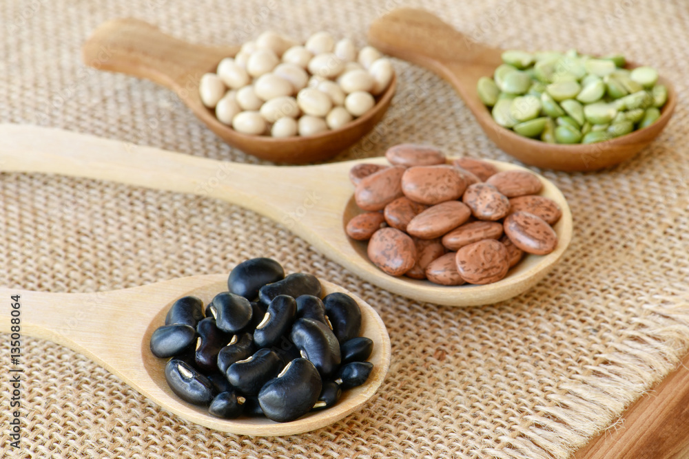 Prepared black bean on wooden spoon with many dried legumes