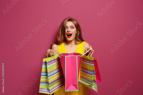 Beautiful young woman with paper bags on color background