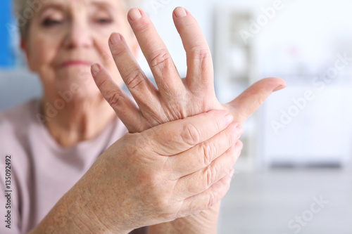 Elderly woman suffering from pain in hand, closeup photo