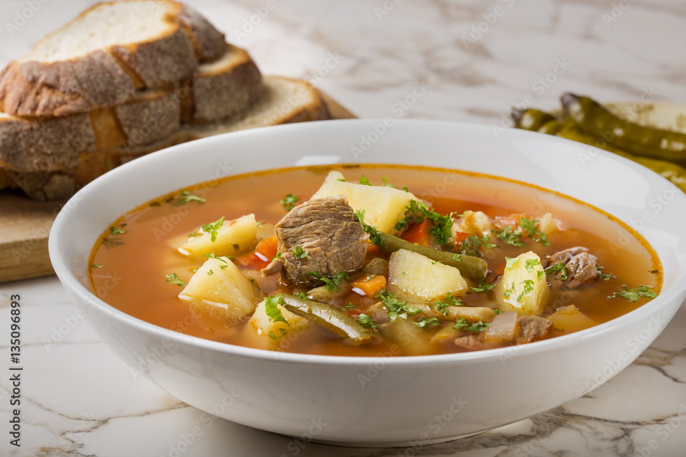 Bowl of vegetable beef soup with bread and hot chilli peppers in Bowl of vegetable beef soup with bread and hot chilli peppers in