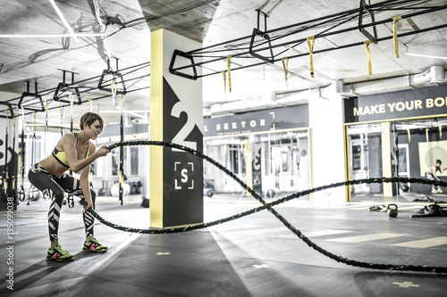 Girl does exercise with fitness rope in gym